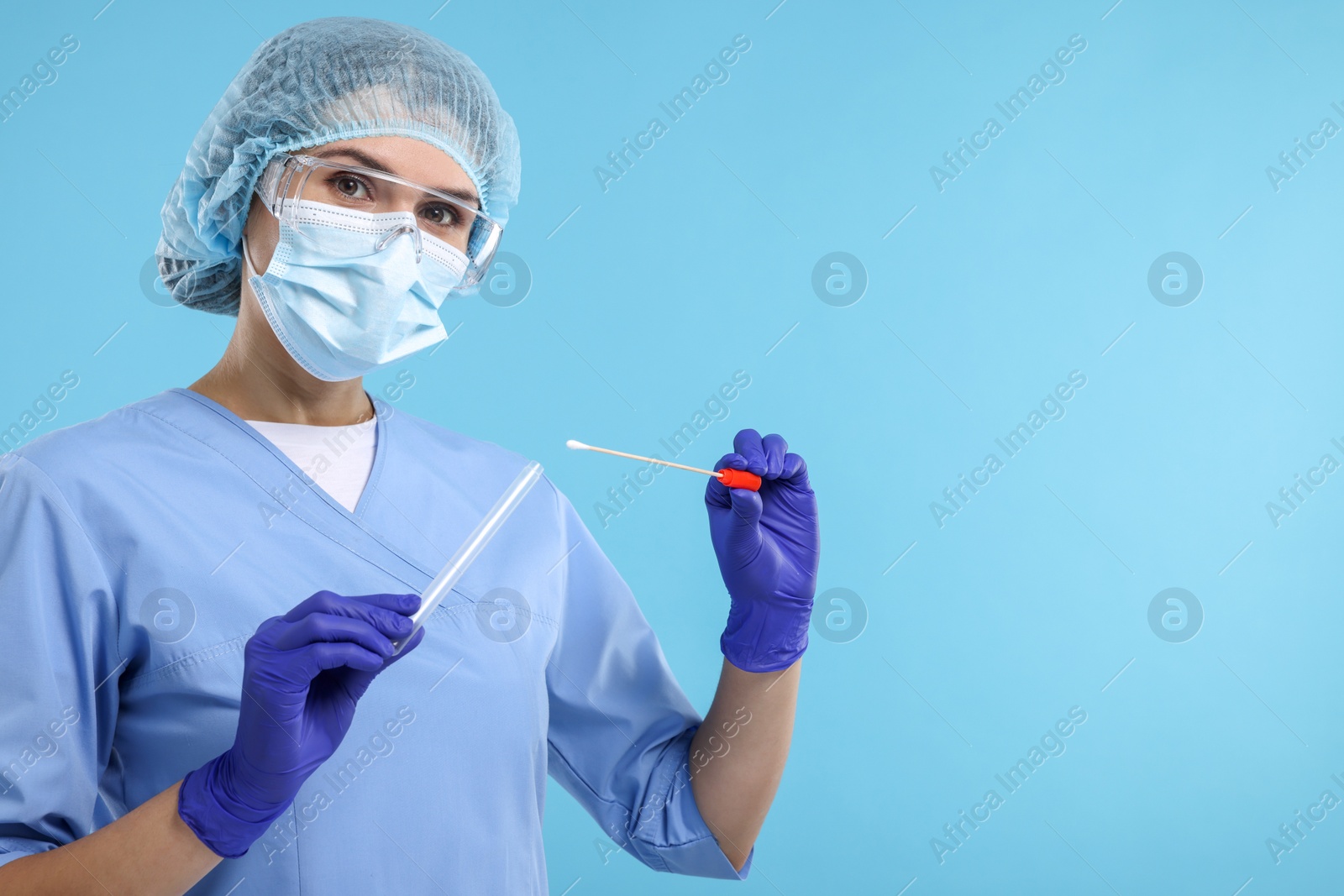 Photo of Laboratory testing. Doctor with cotton swab and tube on light blue background, space for text