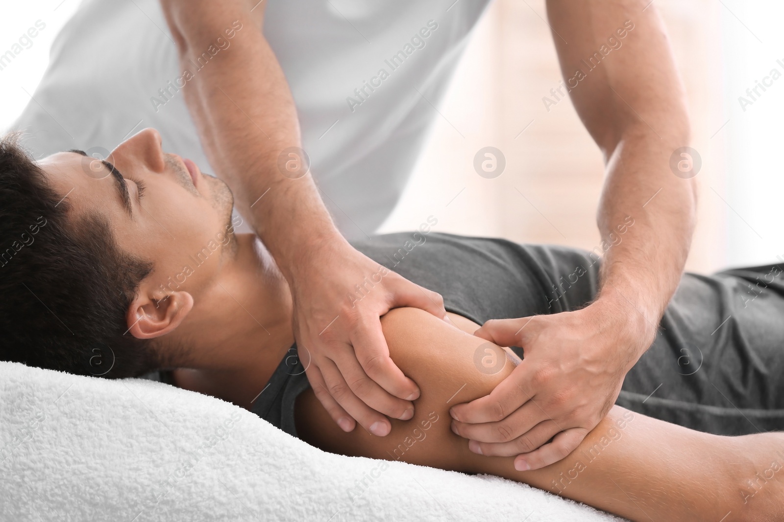 Photo of Young man receiving massage in salon, closeup