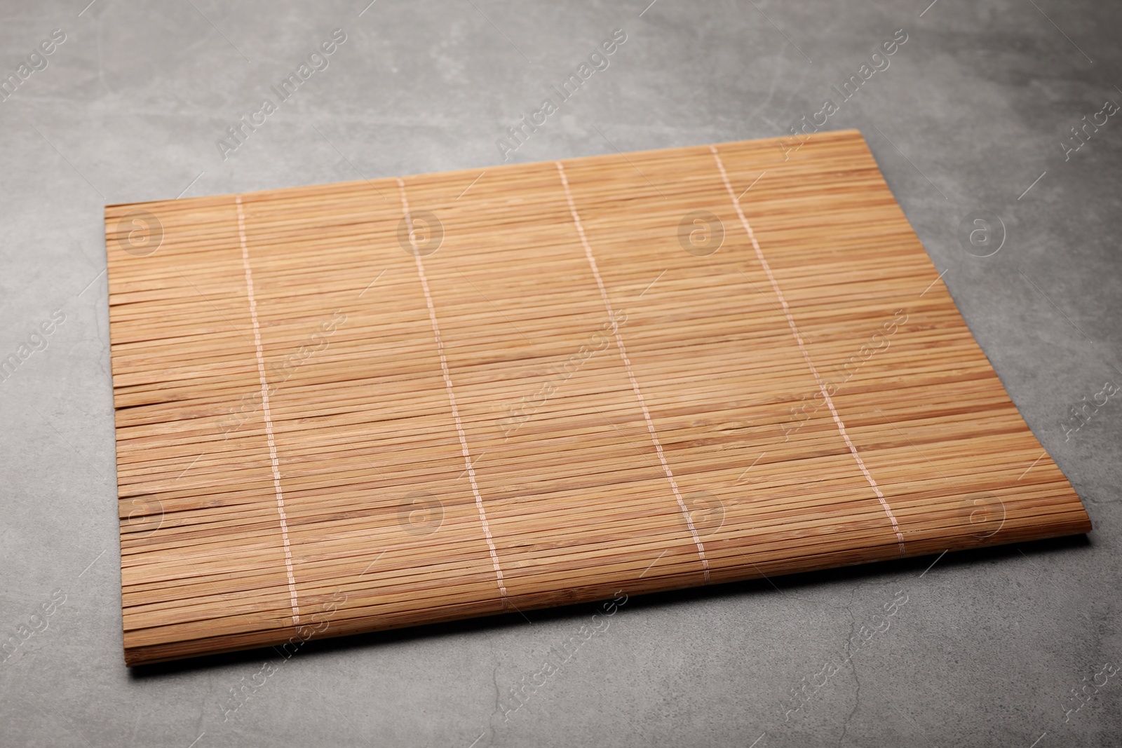 Photo of New clean bamboo mat on grey table