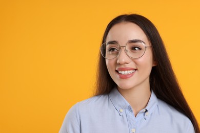 Photo of Beautiful woman wearing glasses on orange background, space for text