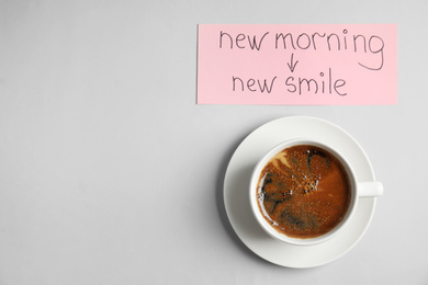 Photo of Delicious coffee and card with text NEW MORNING NEW SMILE on light grey background, flat lay. Space for text