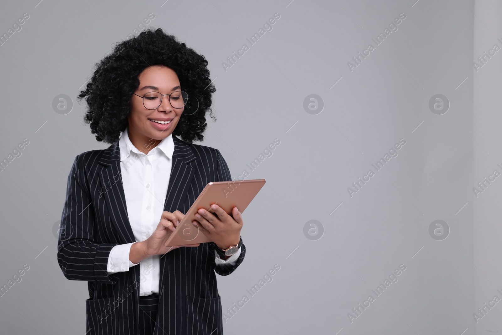 Photo of Young businesswoman with tablet on grey background. Space for text