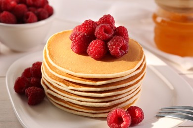 Photo of Stack of tasty pancakes with raspberries on table, closeup