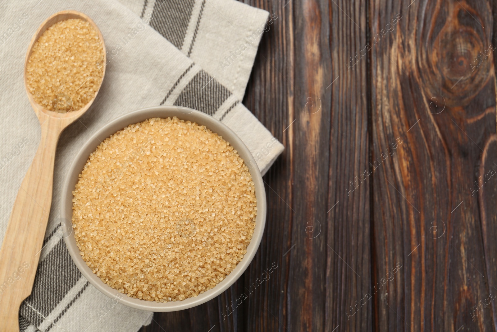 Photo of Brown sugar in bowl and spoon on wooden table, flat lay. Space for text