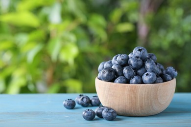 Photo of Tasty fresh blueberries on blue wooden table outdoors, space for text