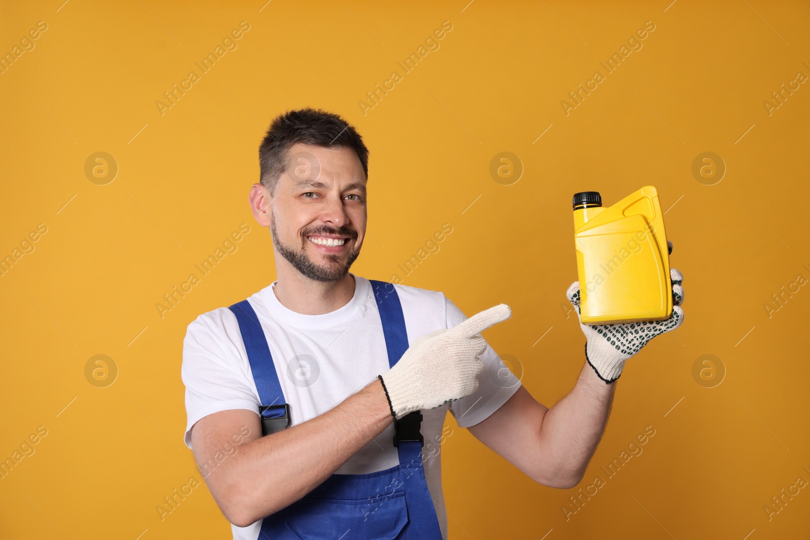 Photo of Man pointing at yellow container of motor oil on orange background