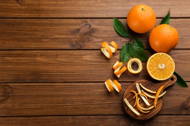 Photo of Orange fruits with peels on wooden table, flat lay. Space for text