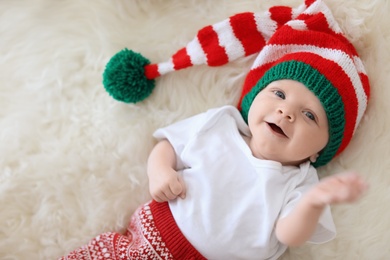 Photo of Adorable baby in Christmas hat on fuzzy rug
