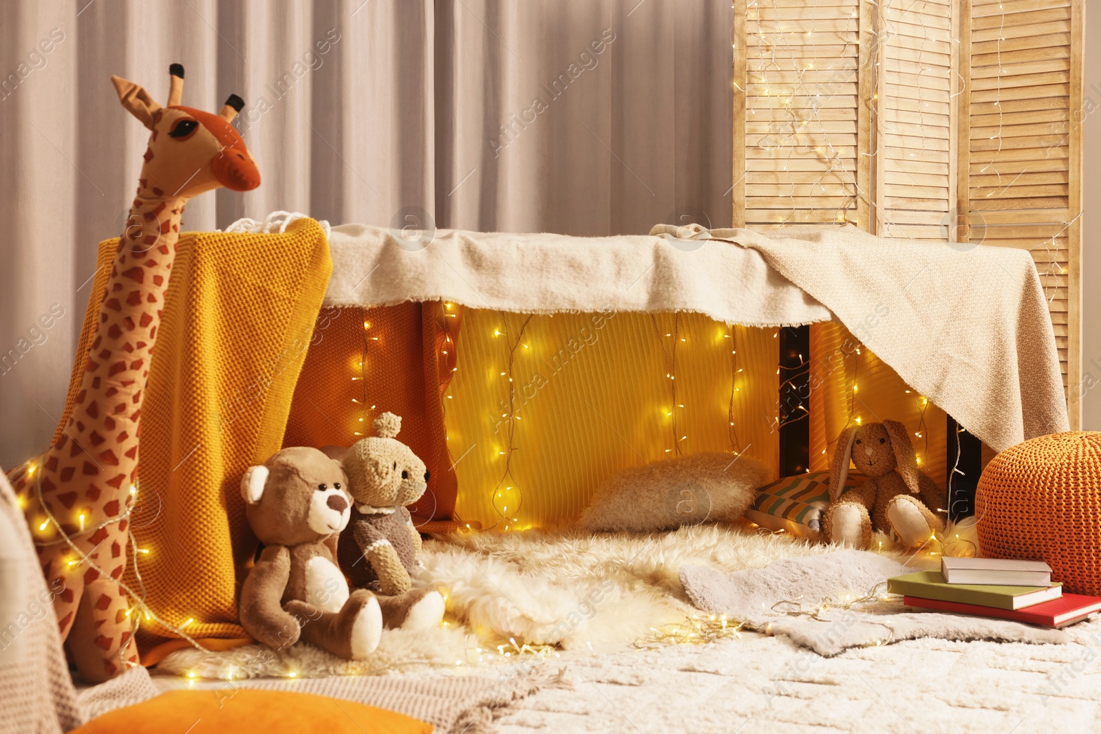 Photo of Beautiful play tent decorated with festive lights and toys at home