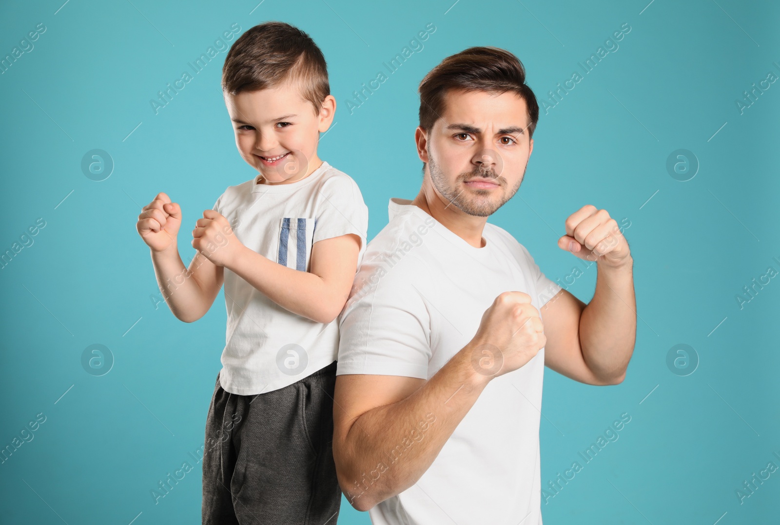 Photo of Portrait of sporty dad and his son on color background