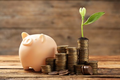 Photo of Stacks of coins with flower and piggy bank on wooden table. Investment concept