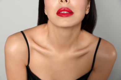 Photo of Young woman wearing beautiful red lipstick on light gray background, closeup