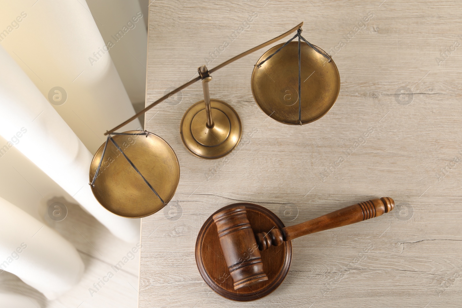 Photo of Law concept. Judge's mallet and scales of justice on light wooden table indoors, top view