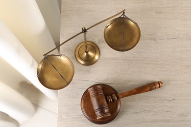 Photo of Law concept. Judge's mallet and scales of justice on light wooden table indoors, top view