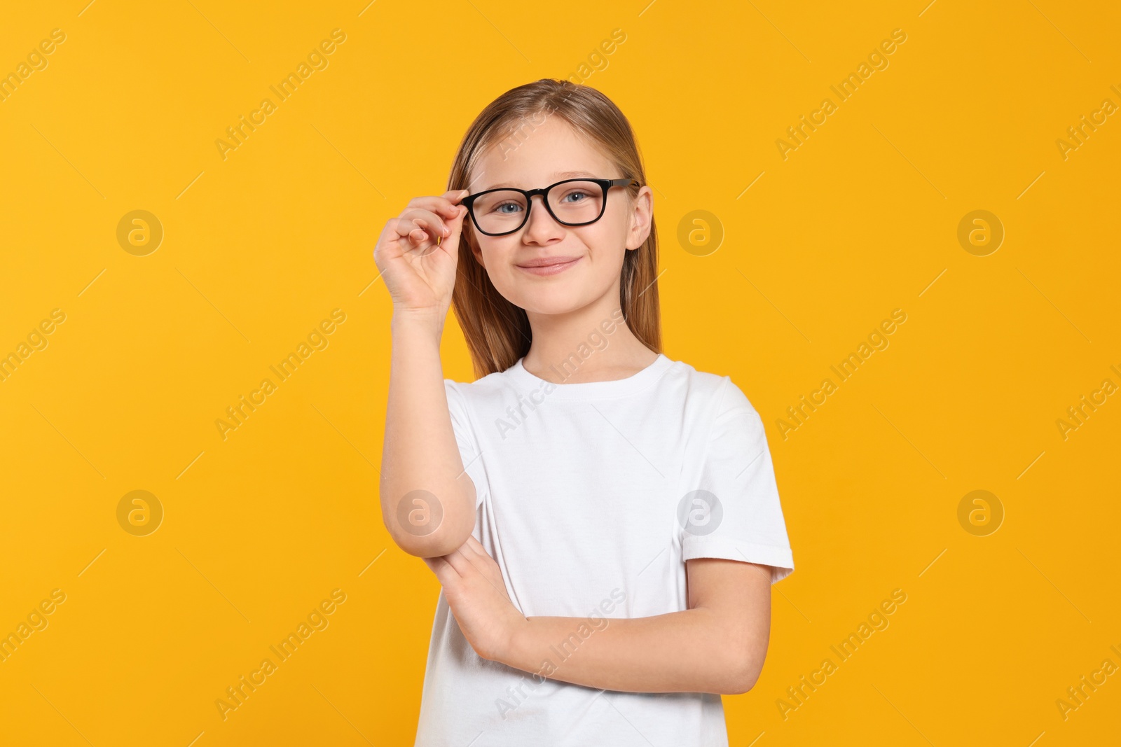 Photo of Portrait of cute girl in glasses on orange background