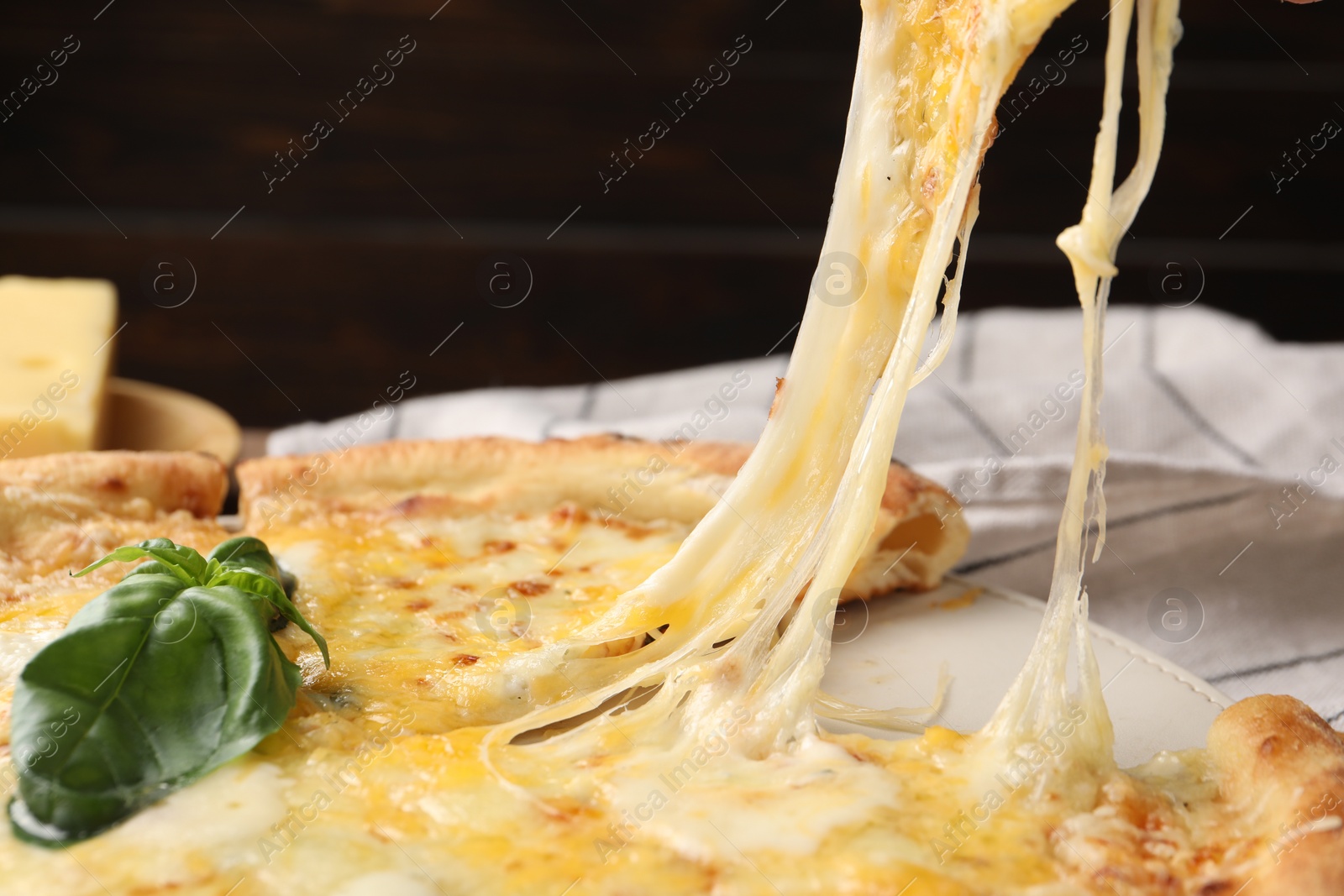 Photo of Taking piece of delicious cheese pizza at table, closeup