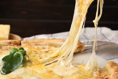 Taking piece of delicious cheese pizza at table, closeup