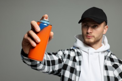 Photo of Handsome man holding used can of spray paint on grey background