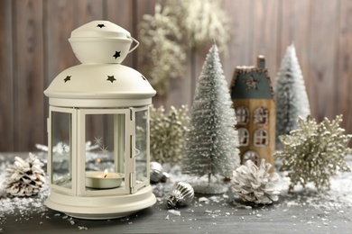 Photo of Christmas lantern with burning candle and festive decor on grey wooden background