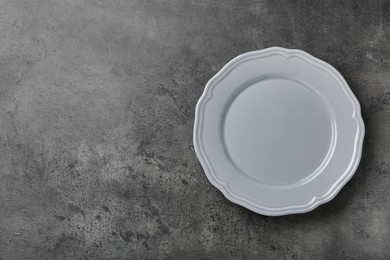 Photo of Clean white plate on grey table, top view. Space for text