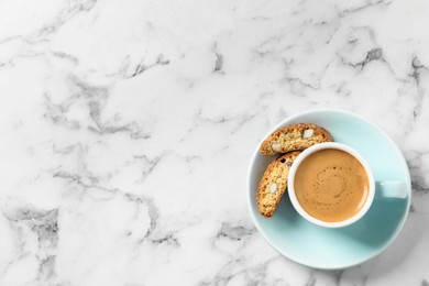 Photo of Tasty cantucci and cup of aromatic coffee on white marble table, top view with space for text. Traditional Italian almond biscuits