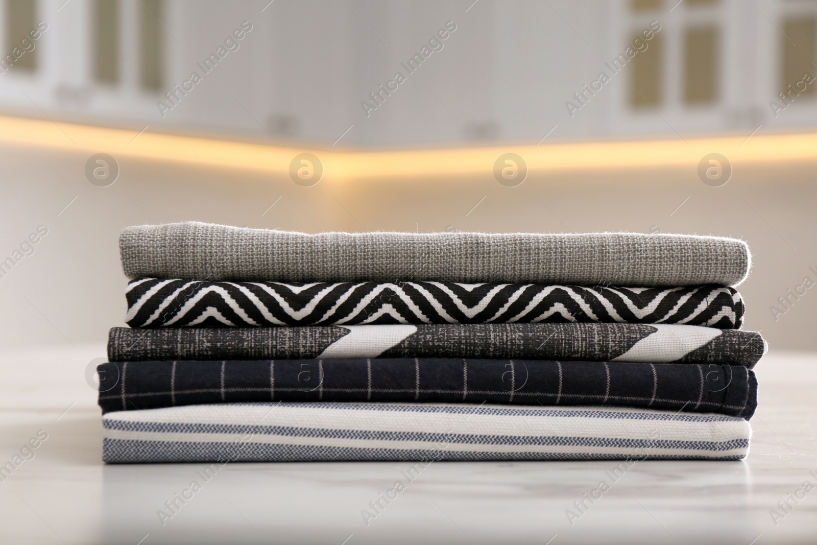 Photo of Stack of soft kitchen towels on white table indoors