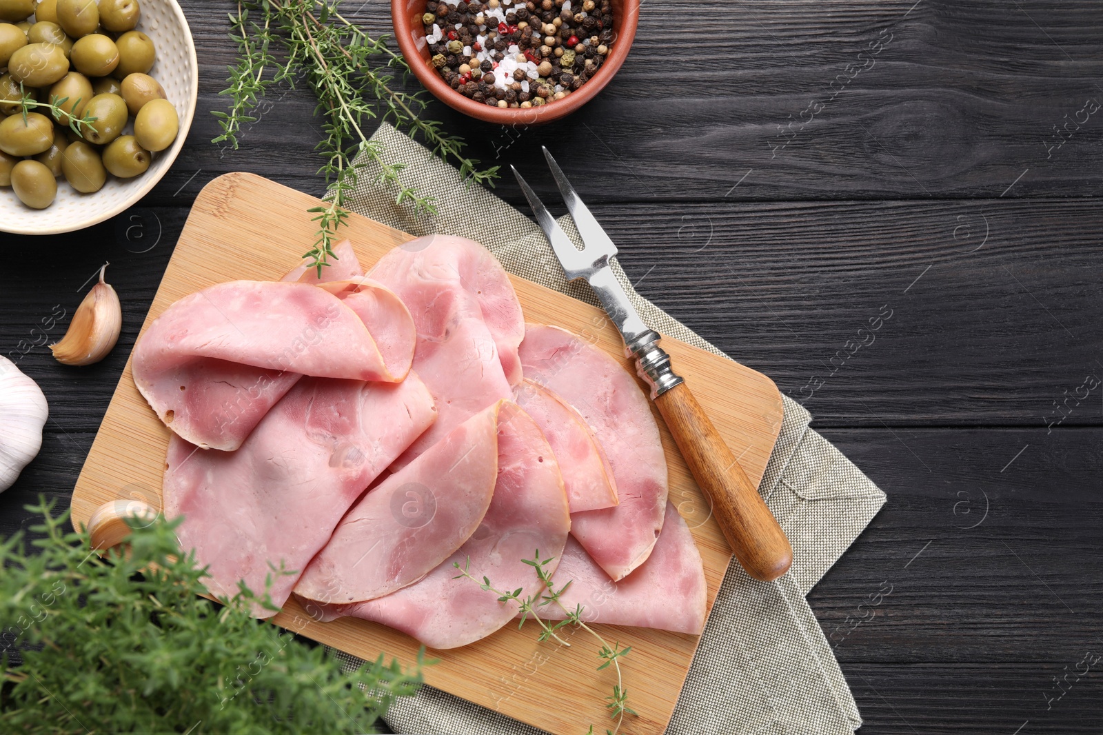 Photo of Slices of delicious ham served with different ingredients on dark wooden table, flat lay. Space for text