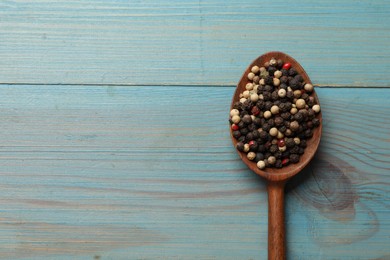 Photo of Aromatic spice. Different peppers in spoon on light blue wooden table, top view. Space for text