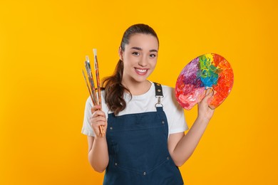 Photo of Woman with painting tools on yellow background. Young artist