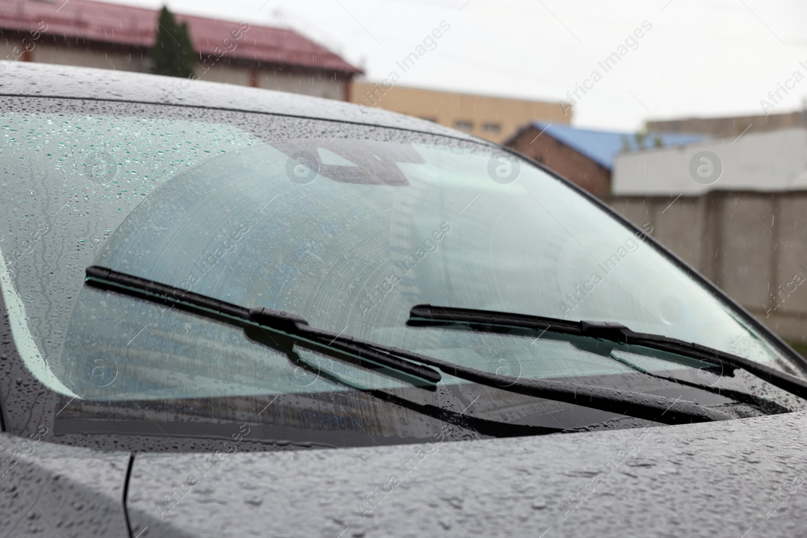 Photo of Car wipers cleaning water drops from windshield glass outdoors, closeup