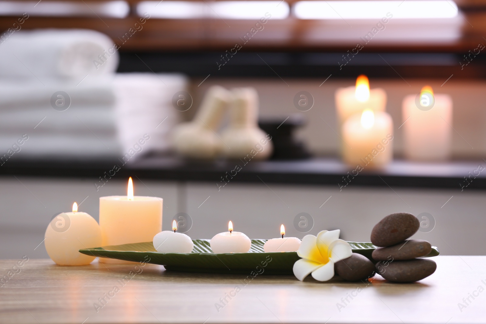 Photo of Composition with candles and stones on table in spa salon. Space for text