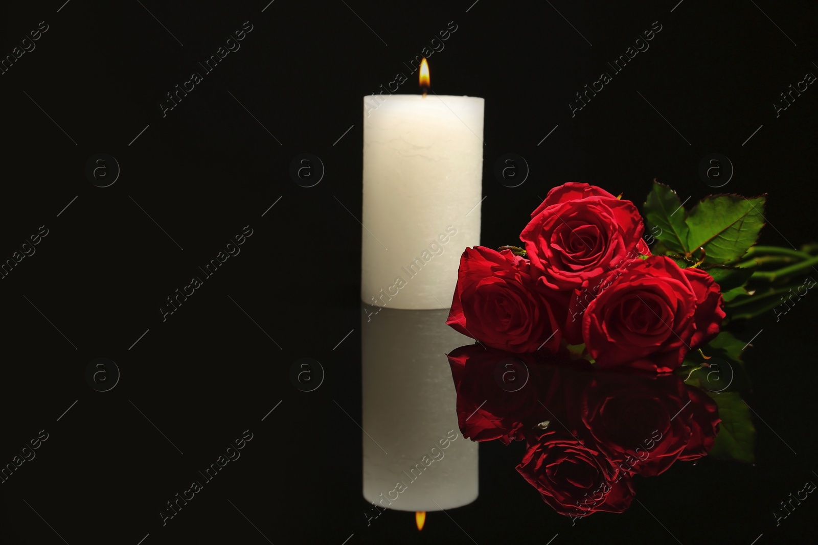 Photo of Beautiful red roses and candle on black background. Funeral symbol