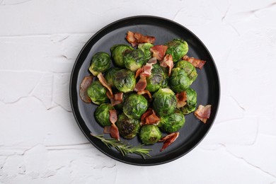 Photo of Delicious roasted Brussels sprouts, bacon and rosemary on white textured table, top view