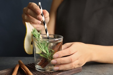Photo of Woman holding glass cocktail with rosemary on table, closeup