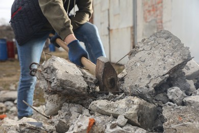 Man breaking stones with sledgehammer outdoors, closeup