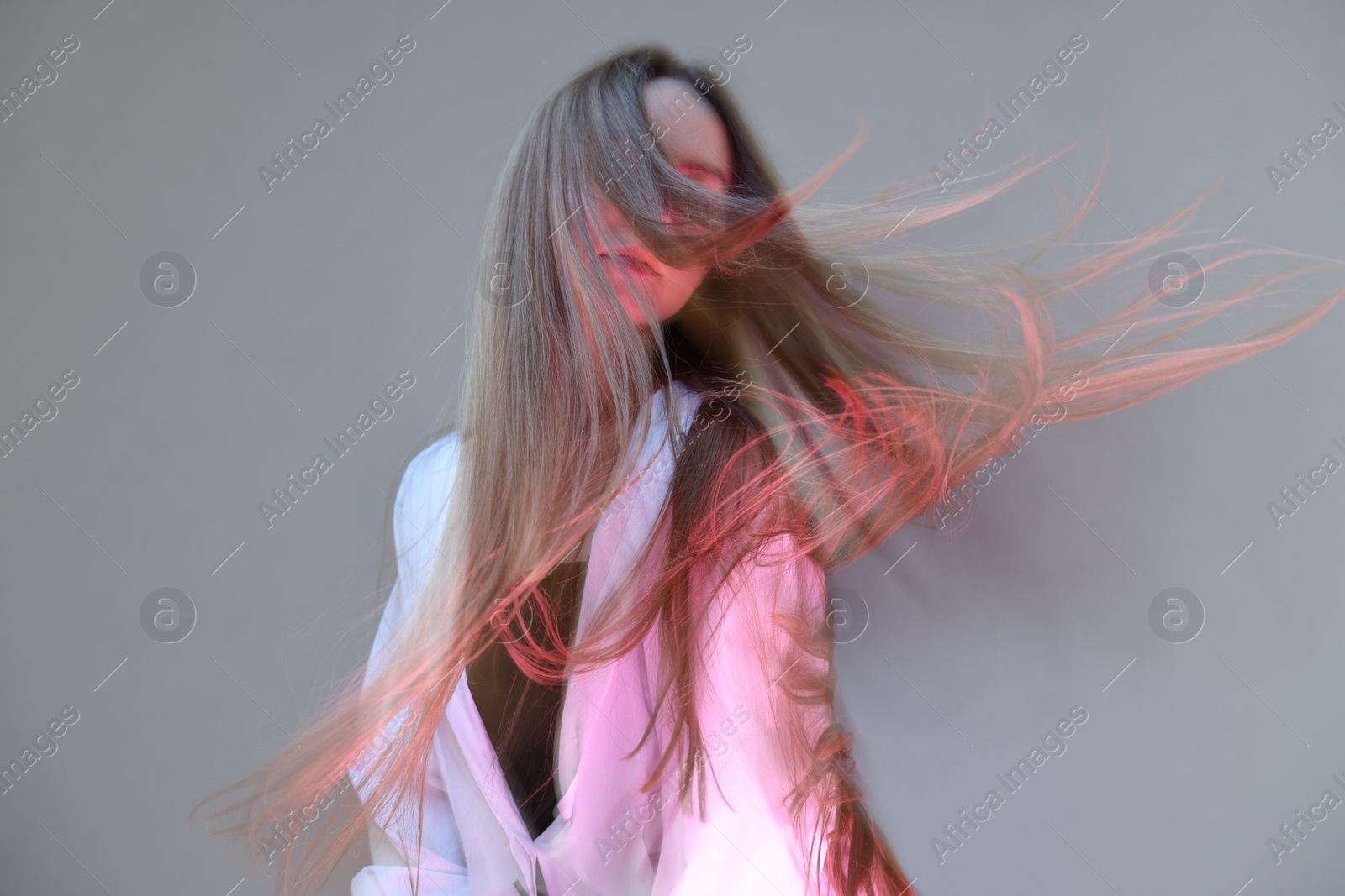 Photo of Fashionable portrait of beautiful young woman on grey background, long-exposure photography