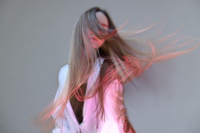 Fashionable portrait of beautiful young woman on grey background, long-exposure photography