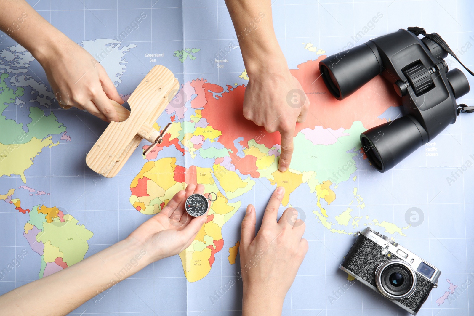 Photo of Women with tourist items planning vacation on world map, top view. Travel agency