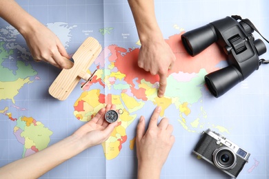 Women with tourist items planning vacation on world map, top view. Travel agency