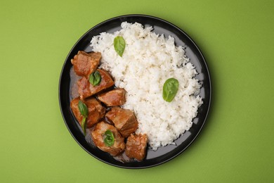 Delicious goulash with rice on green background, top view