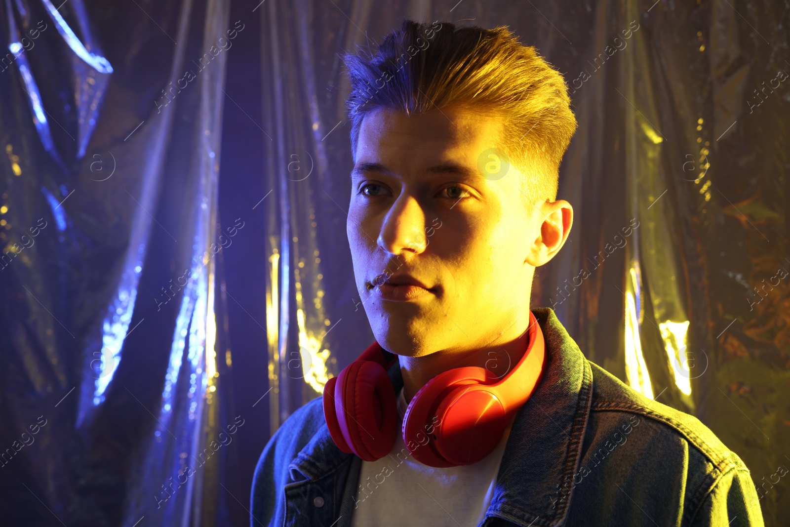 Photo of Young man with headphones in neon lights. Space for text