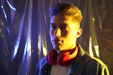 Photo of Young man with headphones in neon lights. Space for text