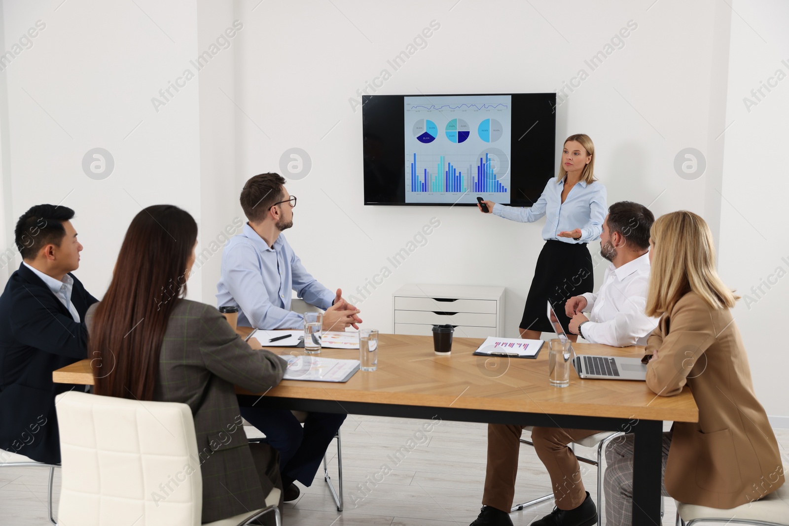 Photo of Businesswoman showing charts on tv screen in office