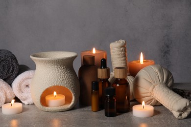 Photo of Aromatherapy. Scented candles and spa products on gray textured table