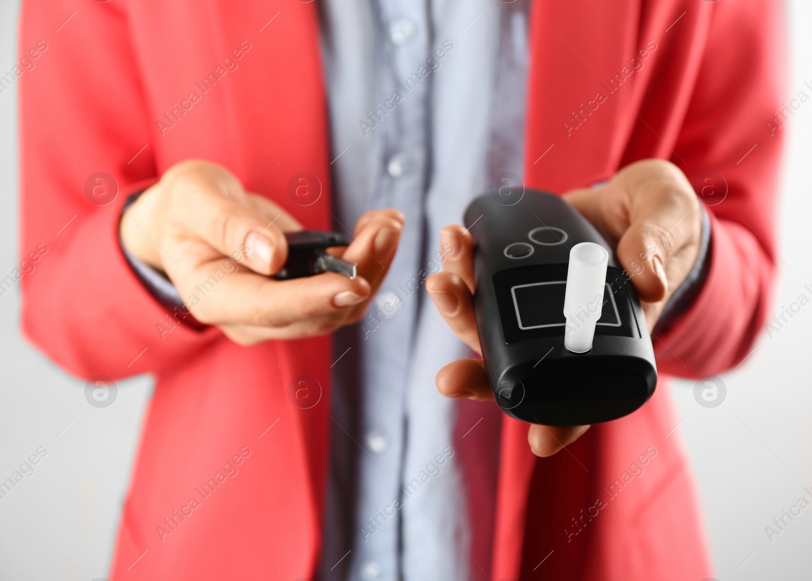 Photo of Woman holding modern breathalyzer and car key on light background, closeup