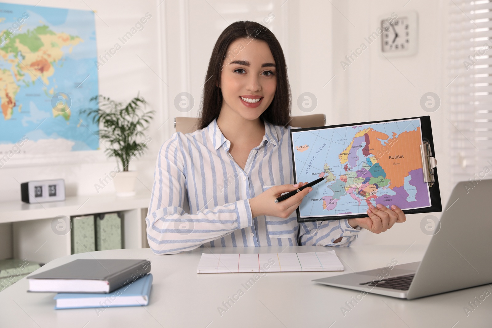 Photo of Happy manager showing map at desk in travel agency