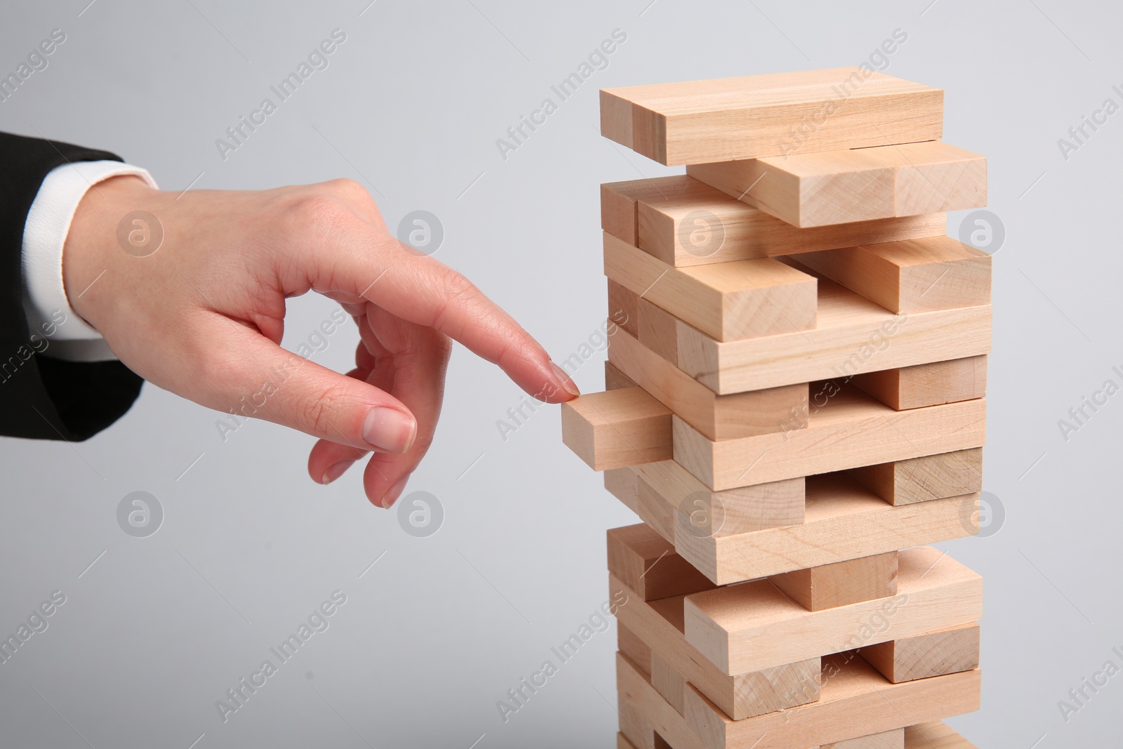 Photo of Woman playing Jenga on light gray background, closeup