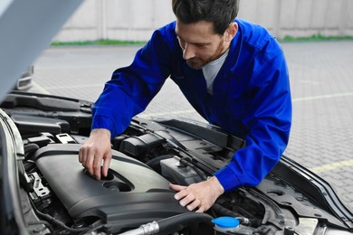 Worker working with modern car engine outdoors