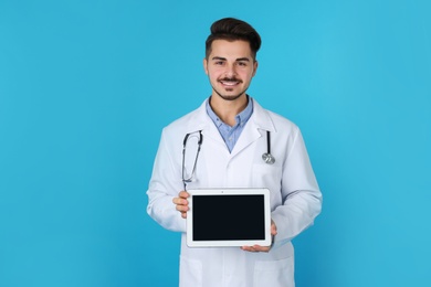 Young medical student with tablet on color background. Space for text