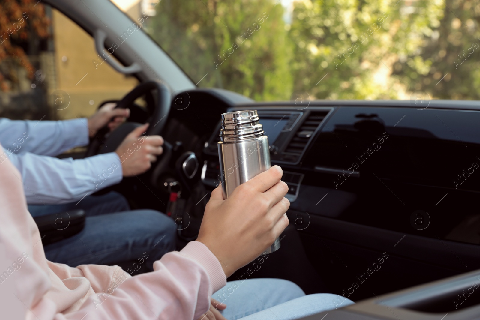 Photo of Woman with thermos on passenger seat of car, closeup